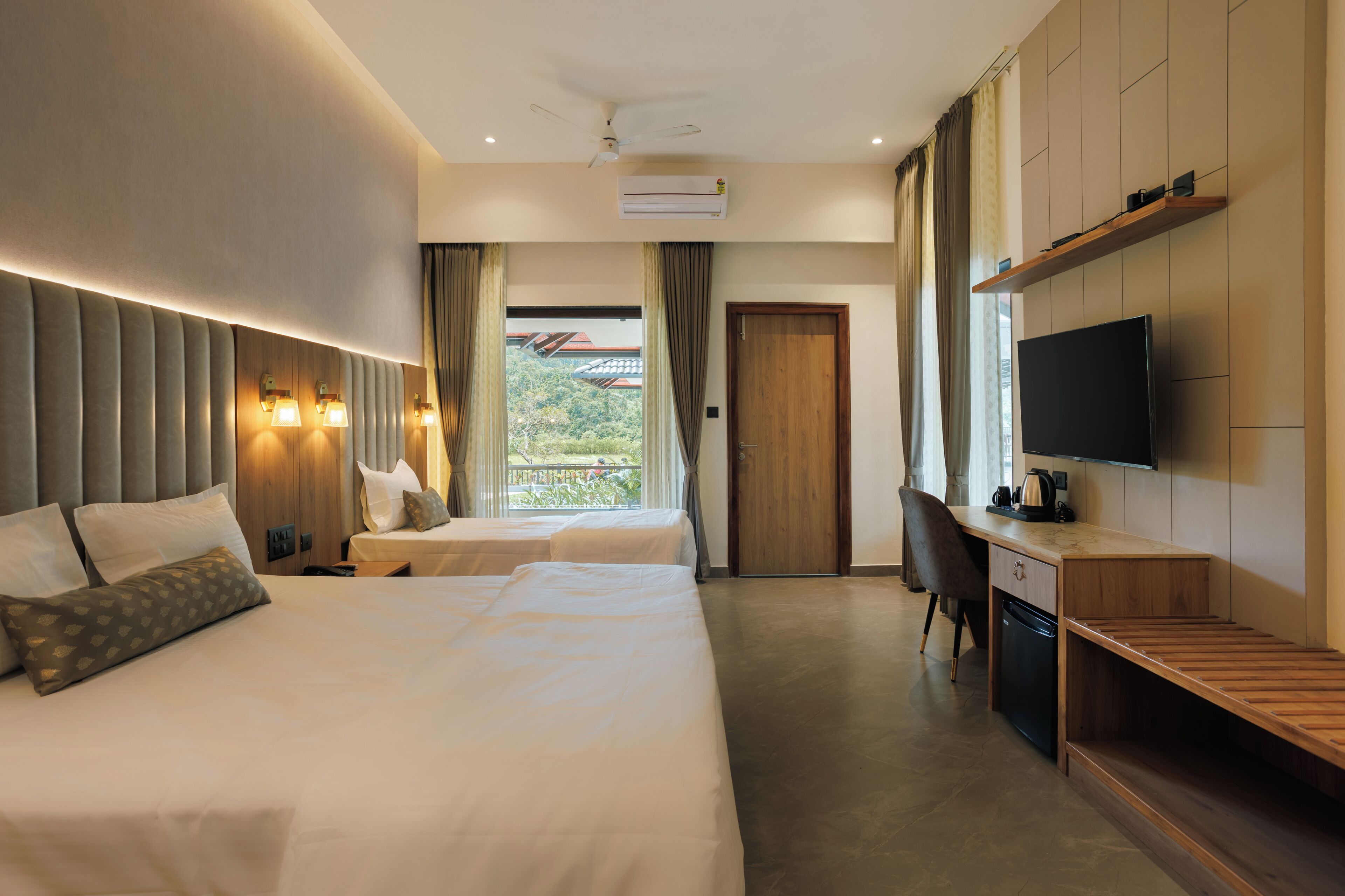 A hotel room with a bed, two bedside tables, a desk, a chair, a TV, and a window with curtains.