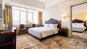 A hotel room with a large bed, a desk, a chair, and a mirror. - Golden Plaza International Hotel (Nanning)