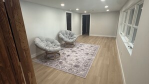 A spacious room with two upholstered chairs, a patterned rug, wooden flooring, and a window with blinds. - Recently Renovated Lakefront Retreat on George Lake (Fairmont)