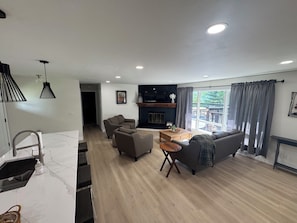 Una sala de estar moderna con chimenea, un sofá, una mesa de centro y un comedor con barra de cocina.