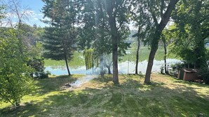 A grassy area with trees, a small pond, and a wooden structure. - Recently Renovated Lakefront Retreat on George Lake (Fairmont)
