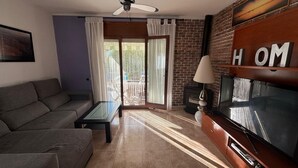 Un salon avec un canapé, une table basse, un téléviseur et une cheminée.