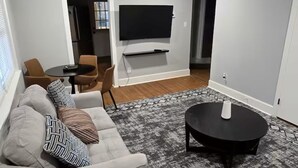 Ein modernes Wohnzimmer mit einem grauen Sofa, einem schwarzen Couchtisch und einem flachbildfernseher an der Wand.