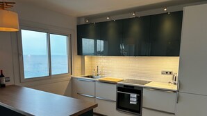 Una cocina moderna con un ventanal grande, armarios blancos y una encimera de madera.