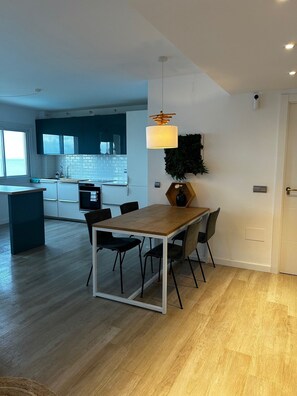 A modern kitchen with a dining area, featuring a wooden table and chairs, a pendant light, and a view of the kitchen through a window. - Comfort with the best ocean view at the Marina Balcony (Benalmadena)