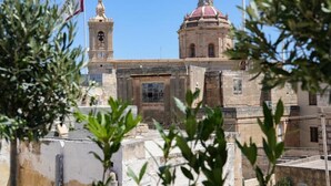 A historic building with a bell tower and a dome, surrounded by greenery. - Fourteen Guesthouse  (Żejtun)