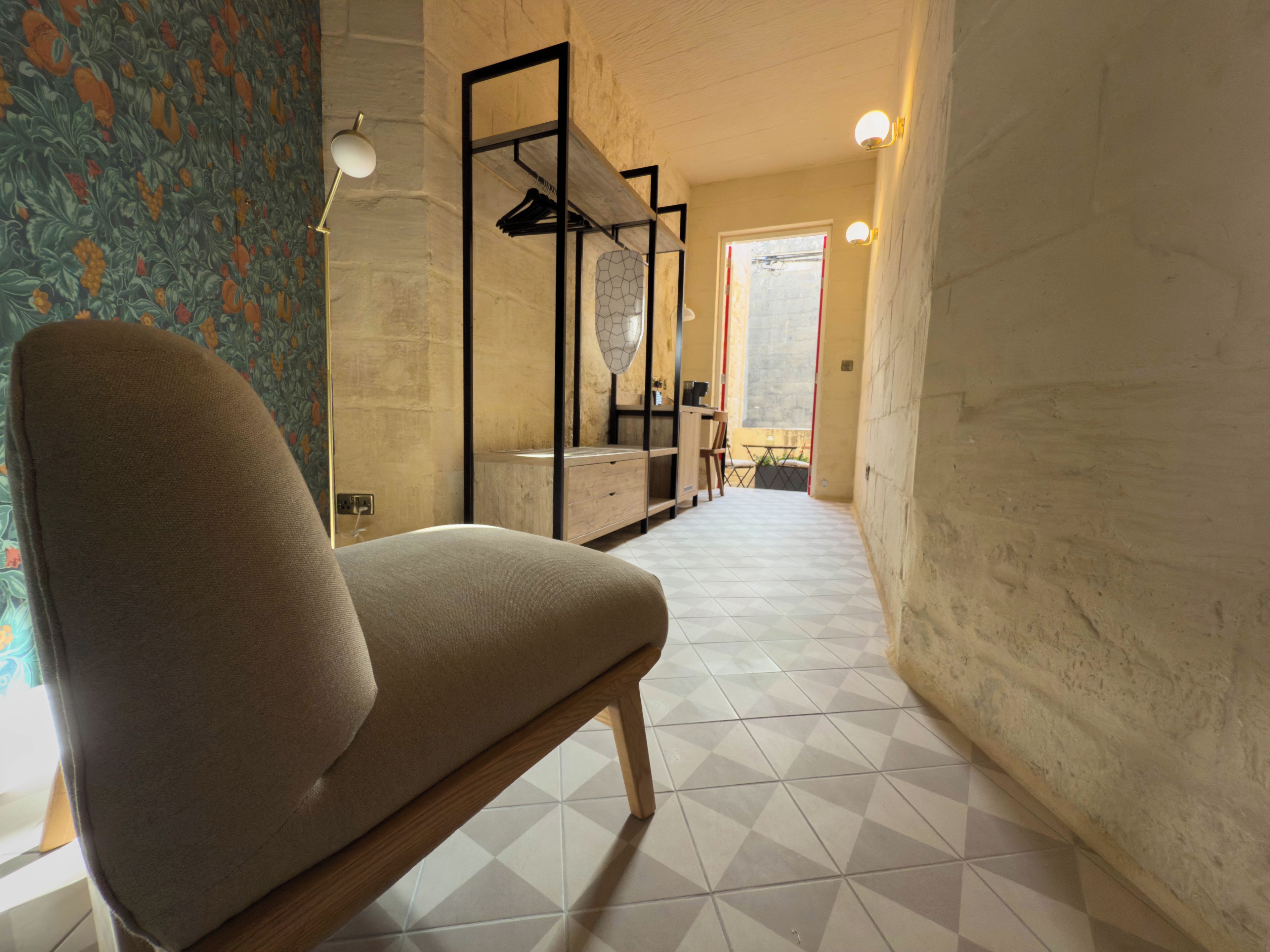 A modern interior with a sofa, a patterned wall, and a tiled floor.