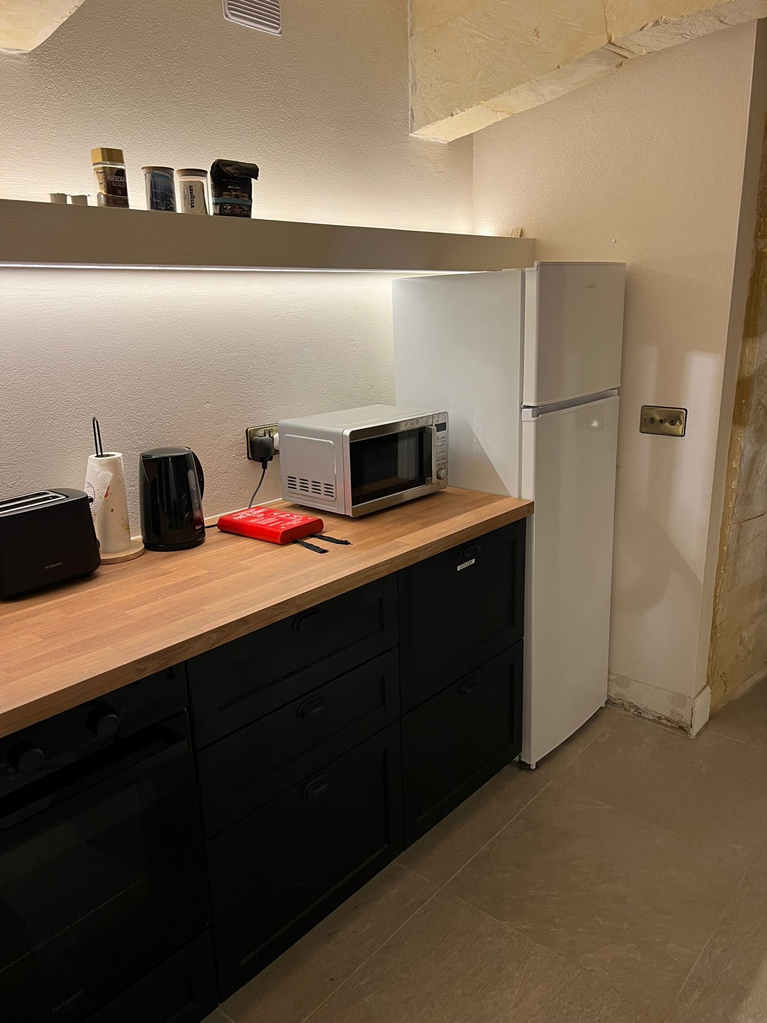 A compact kitchen with a microwave, toaster, and a small refrigerator.