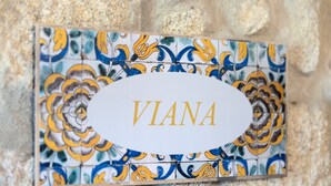 Eine Namensplatte mit dem Schriftzug 'VIANA' an einer gefliesten Wand.