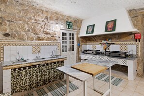 Una cocina con pared de piedra, un fregadero, una estufa y un armario.