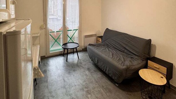 A compact living space with a sofa, a small round table, and a kitchenette area. - Little Arras — 25 m² apartment in Arras center (Arras)