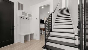 Ein modernes Interieur mit Treppe, einer Bank und einem an der Wand montierten Fernseher.