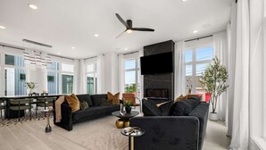 Ein modernes Wohnzimmer mit einem schwarzen Sofa, einem runden Couchtisch und einem Kamin.