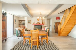Uma sala de jantar com mesa e cadeiras de madeira, um lustre e uma escada.