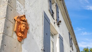 A building facade with a weathered wall, a decorative relief, and shutters.