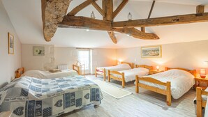 A bedroom with two wooden beds, a large window, and exposed wooden beams.