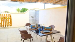 Eine Terrasss mit Esstisch, Stühlen, einem Holzzaun und einem gefliesten Boden.
