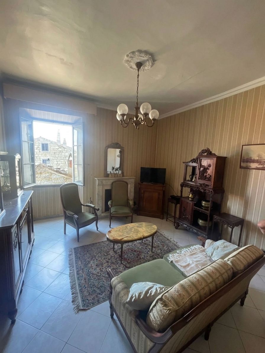 Una sala de estar con sofá, dos sillones, una mesita de centro, chimenea, televisor y un mueble de madera.