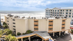 Et hotel med flere etager, fladt tag, klimaanlæg og en parkeringsplads med skiltning for 'OUTRIGGER BEACH'.