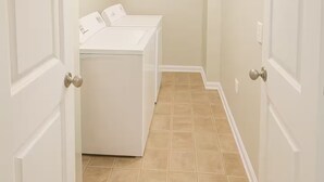 A laundry room with a washing machine and dryer, white walls, and a tiled floor. - Home-away-from-home, Entire home in West Des Moines, Iowa (West Des Moines)