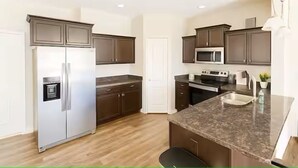 A modern kitchen with dark cabinets, stainless steel appliances, and a granite countertop. - Home-away-from-home, Entire home in West Des Moines, Iowa (West Des Moines)