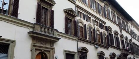 Un edificio de varias plantas con un estilo arquitectónico clásico, con ventanas en arco y una entrada central con una puerta decorativa.