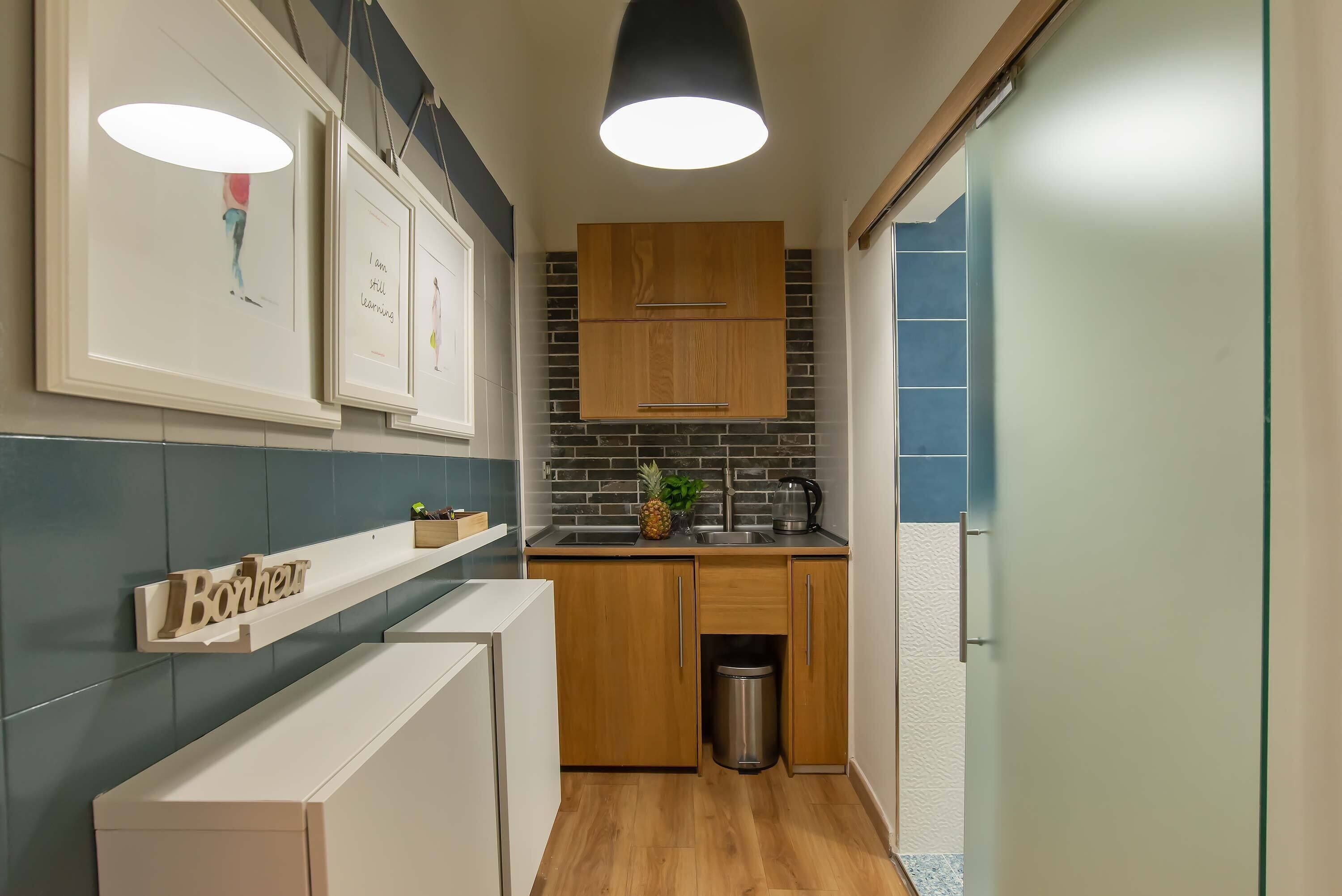 Una cucina compatta con mobili in legno, un lavandino in acciaio inox e un piccolo cestino.
