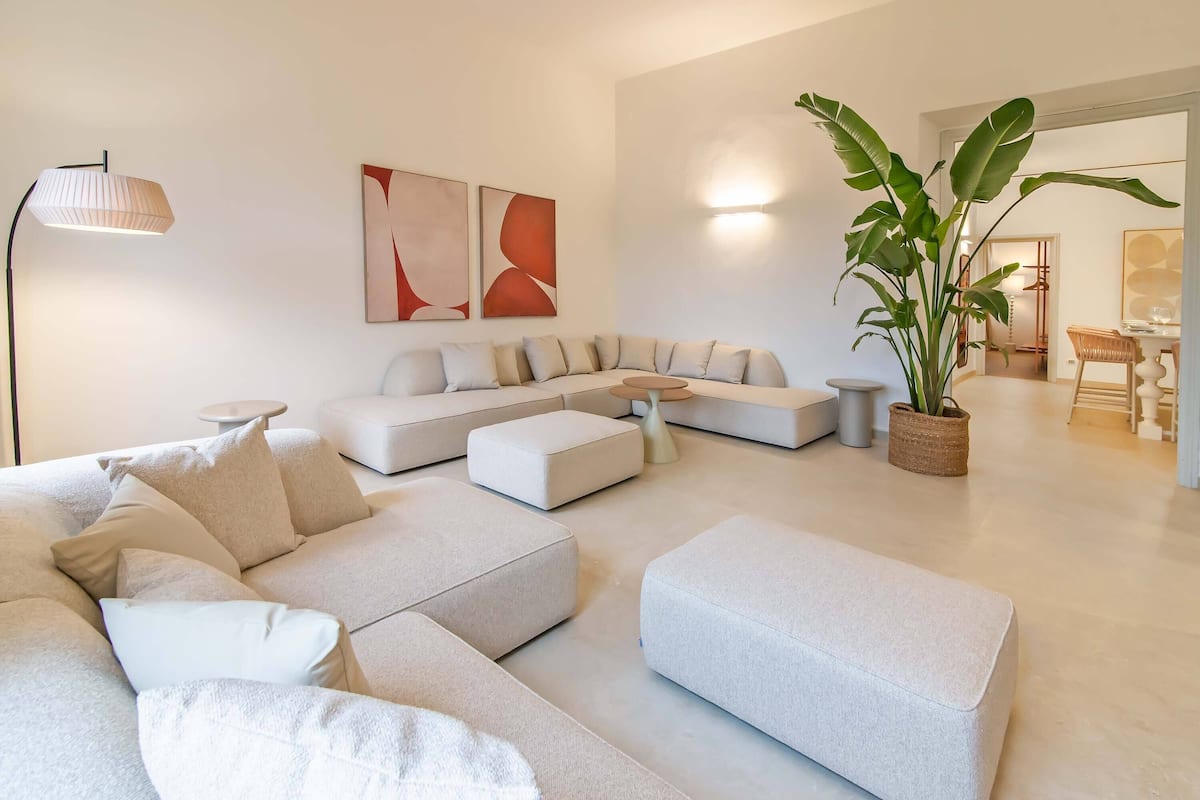 A modern living room with a sectional sofa, ottomans, a coffee table, and a large plant.