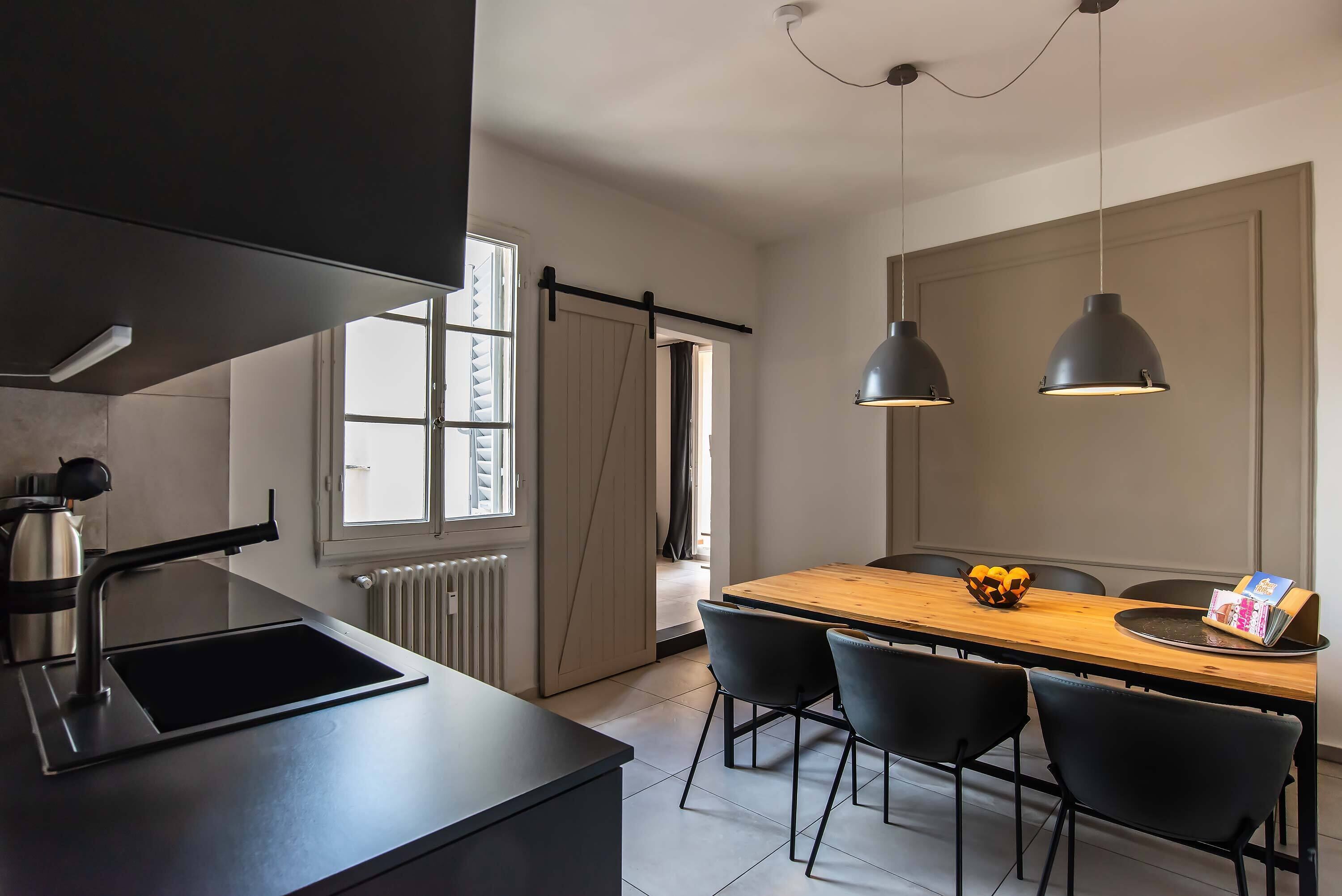 Eine moderne Küche mit schwarzem Arbeitsplatz, integriertem Spülbecken und einem Holzespeisebereich mit vier Stühlen.