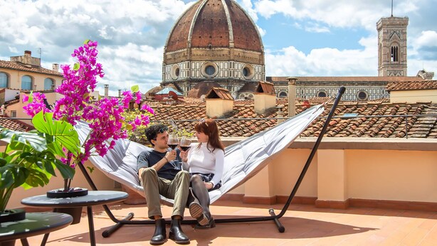 Um casal relaxando em uma rede com vista para um edifício histórico.