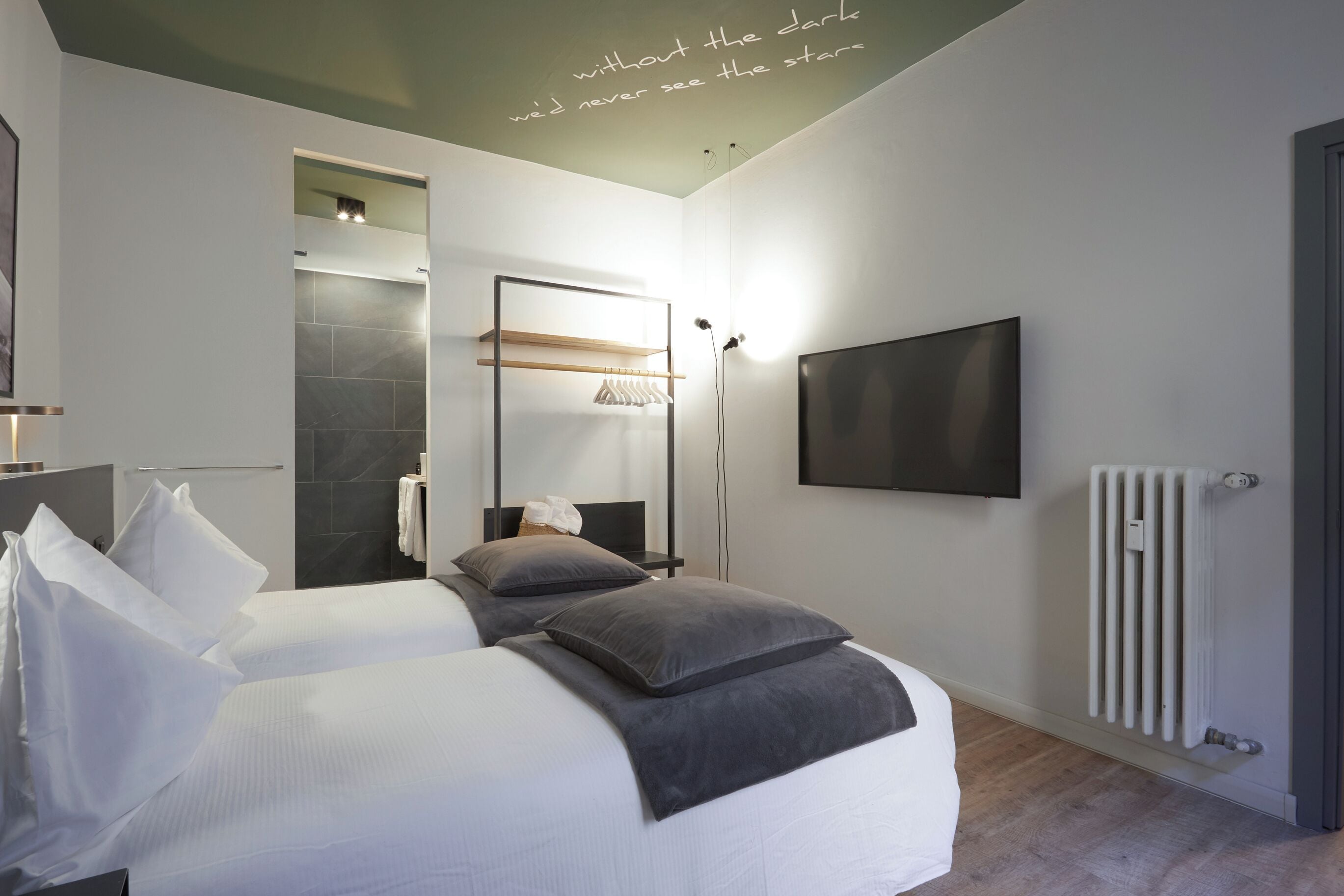 Et moderne hotelværelse med to senge, et fjernsyn, en bruser og udsigt til himlen.