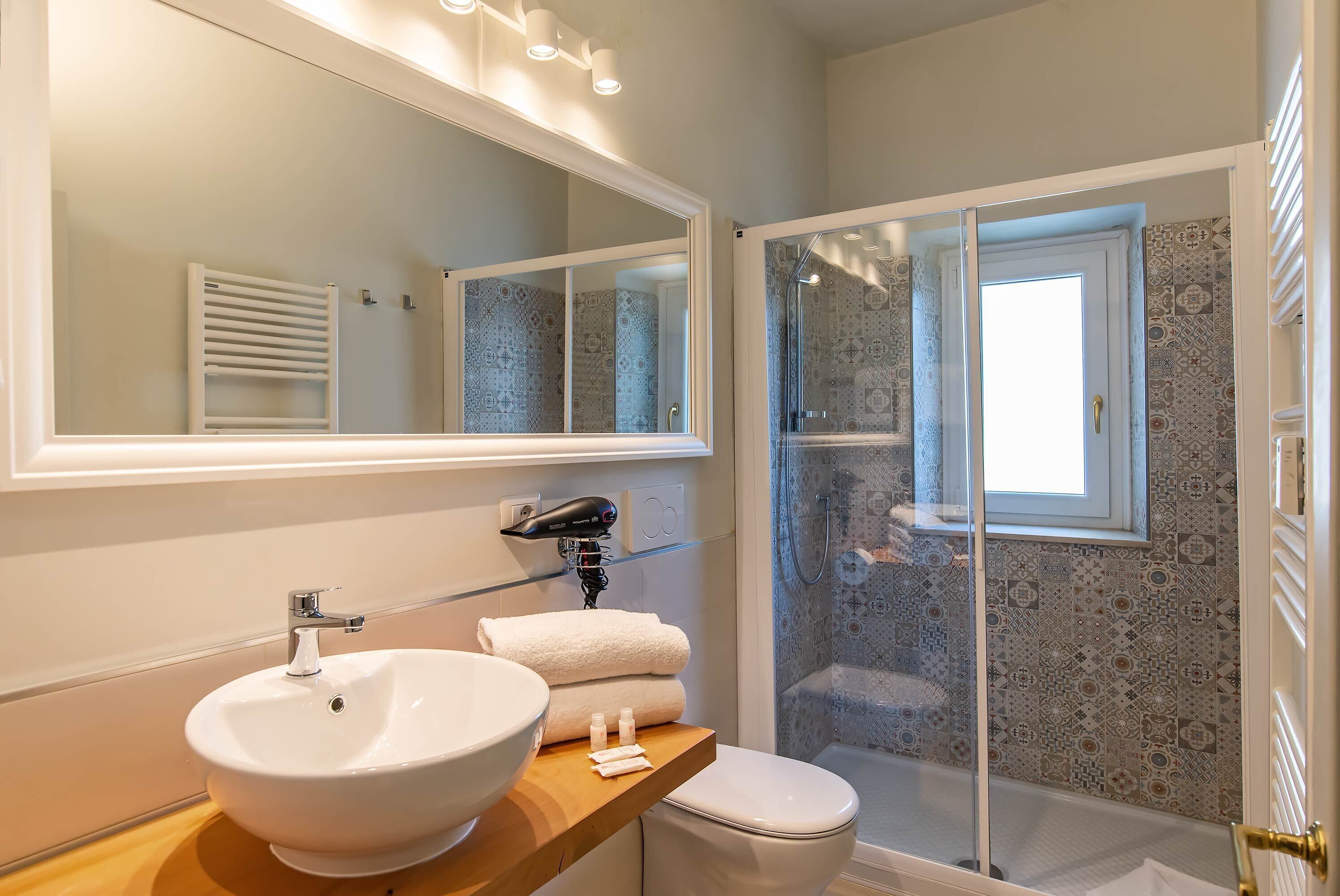 A bathroom with a large mirror, a sink, a toilet, and a shower area.