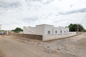 A single-story building with a flat roof, a stone wall, and a paved driveway. - Villa Dafne No.2 with Sea View, Wi-Fi and Air Conditioning 'Residence Pietrantonio' (Marina di Lizzano)