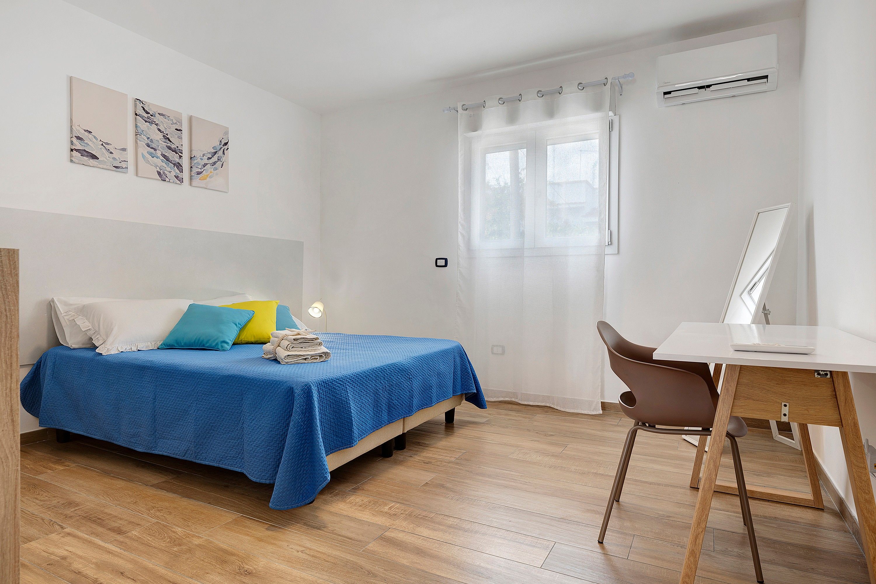 A bedroom with a bed, a desk, and a chair.