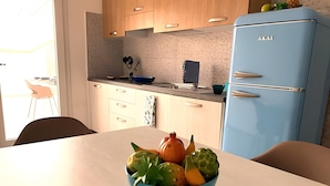 Una cocina moderna con armarios de madera, un refrigerador azul y una mesa con fruteros.