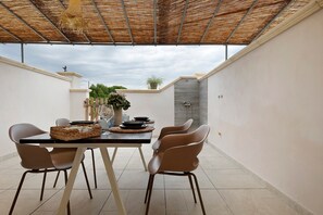 Un patio al aire libre con una mesa dispuesta para comer, rodeado de sillas.