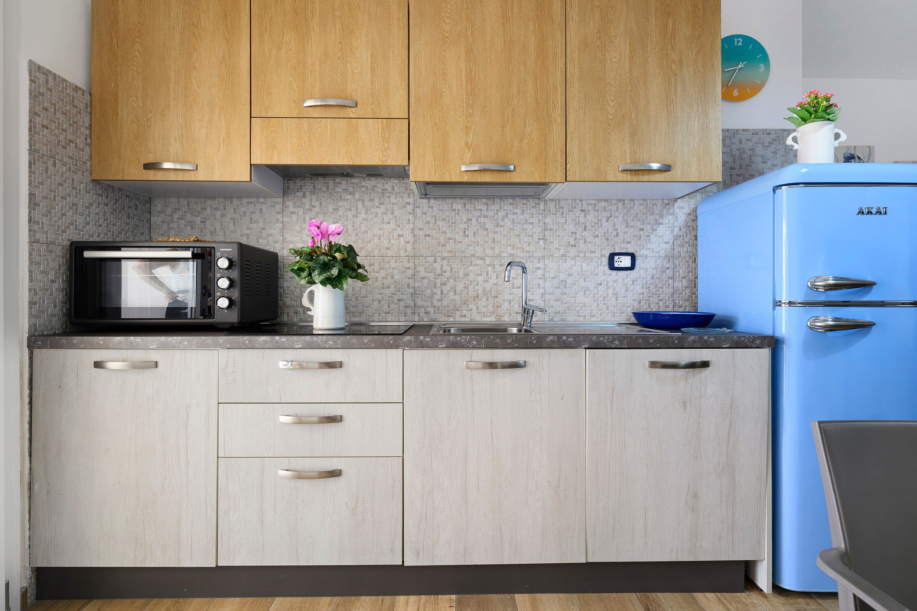 A kitchen with wooden cabinets, a black microwave, a sink, and a blue refrigerator.