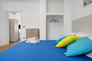 A bedroom with a bed, a wooden dresser, a hanging clothes rack, and a door leading to another room. - Villa Dafne No.2 with Sea View, Wi-Fi and Air Conditioning 'Residence Pietrantonio' (Marina di Lizzano)