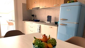 Una cucina moderna con mobili in legno, un frigorifero blu e un tavolo con una ciotola di frutta.