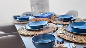 Un tavolo apparecchiato con piatti, ciotole e un bicchiere, il tutto in blu.