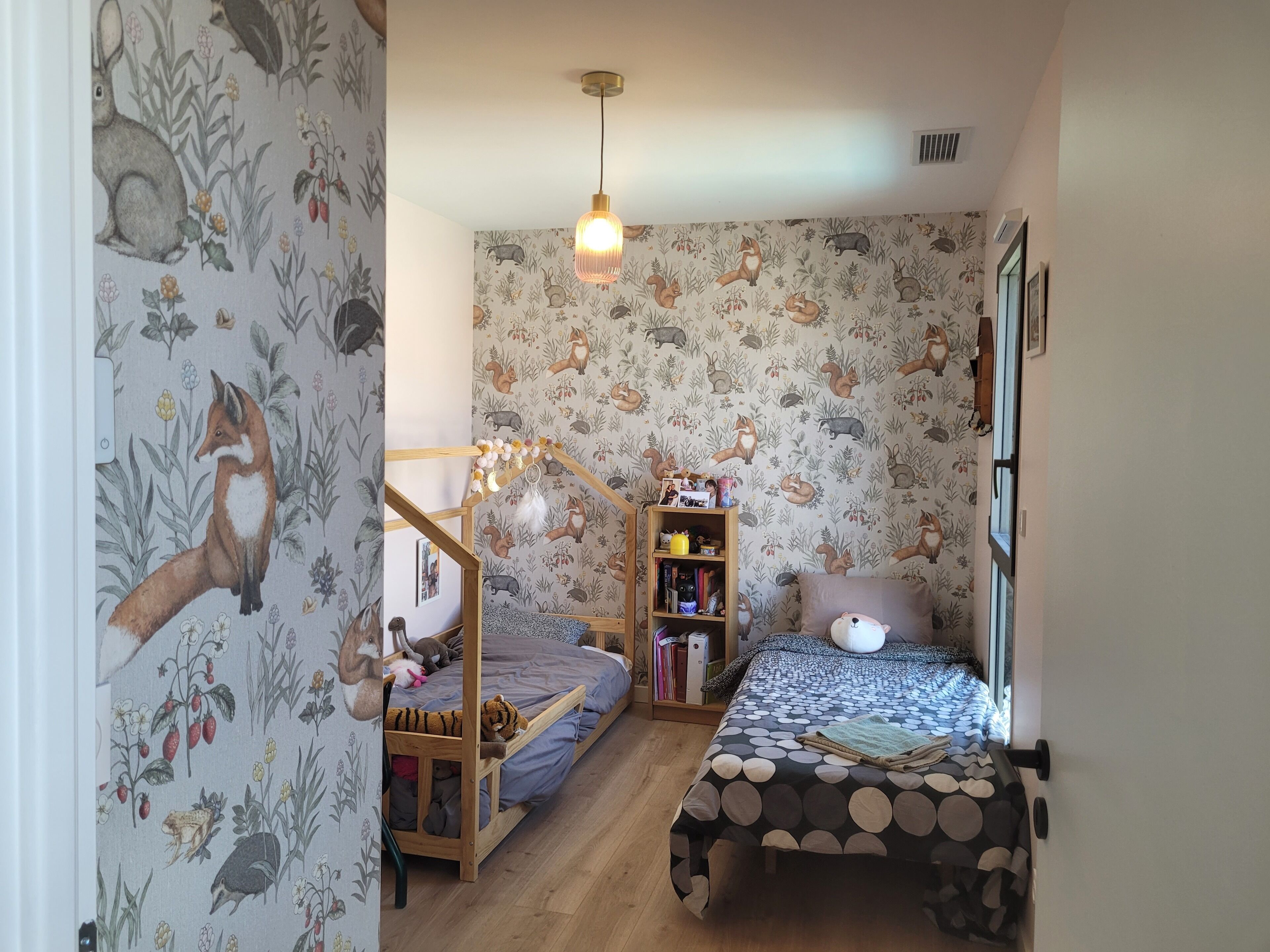 Un dormitorio infantil con una cama litera, un pequeño escritorio de madera y una estantería.