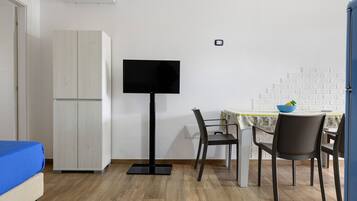 A room with a bed, a TV, a dining table with chairs, and a wardrobe.