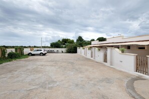 A residential area with a paved driveway, a white car parked, and a building with a gated entrance. - Villa Ninfea No.5 with Sea View, Wi-Fi and Air Conditioning 'Residence Pietrantonio' (Marina di Lizzano)