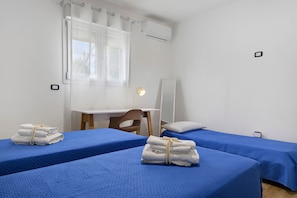 A hotel room with two single beds, a desk, a chair, a mirror, and an air conditioning unit. - Villa Ninfea No.5 with Sea View, Wi-Fi and Air Conditioning 'Residence Pietrantonio' (Marina di Lizzano)