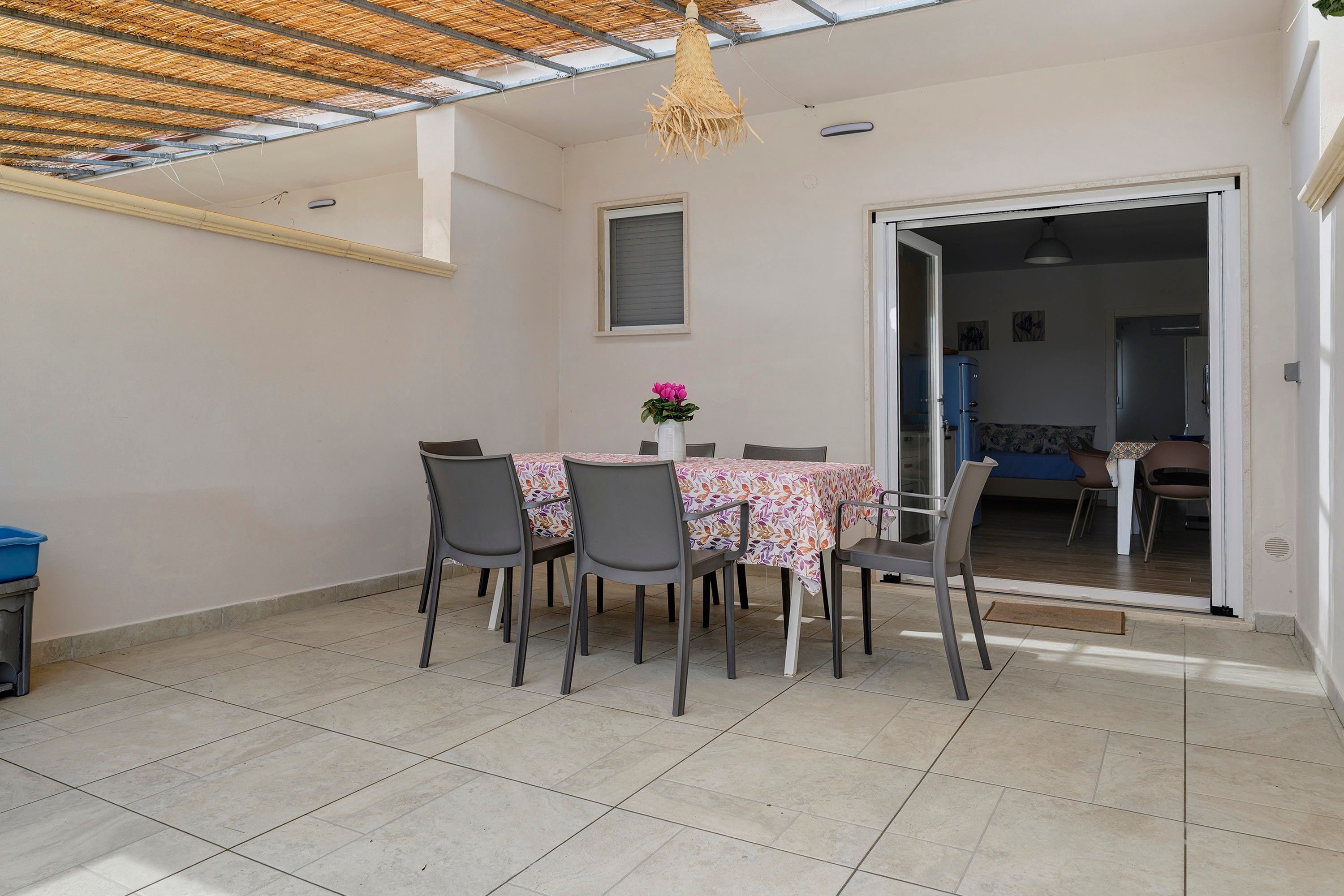 Un espace repas comprenant une table et des chaises, un luminaire suspendu et une vue sur une autre pièce.