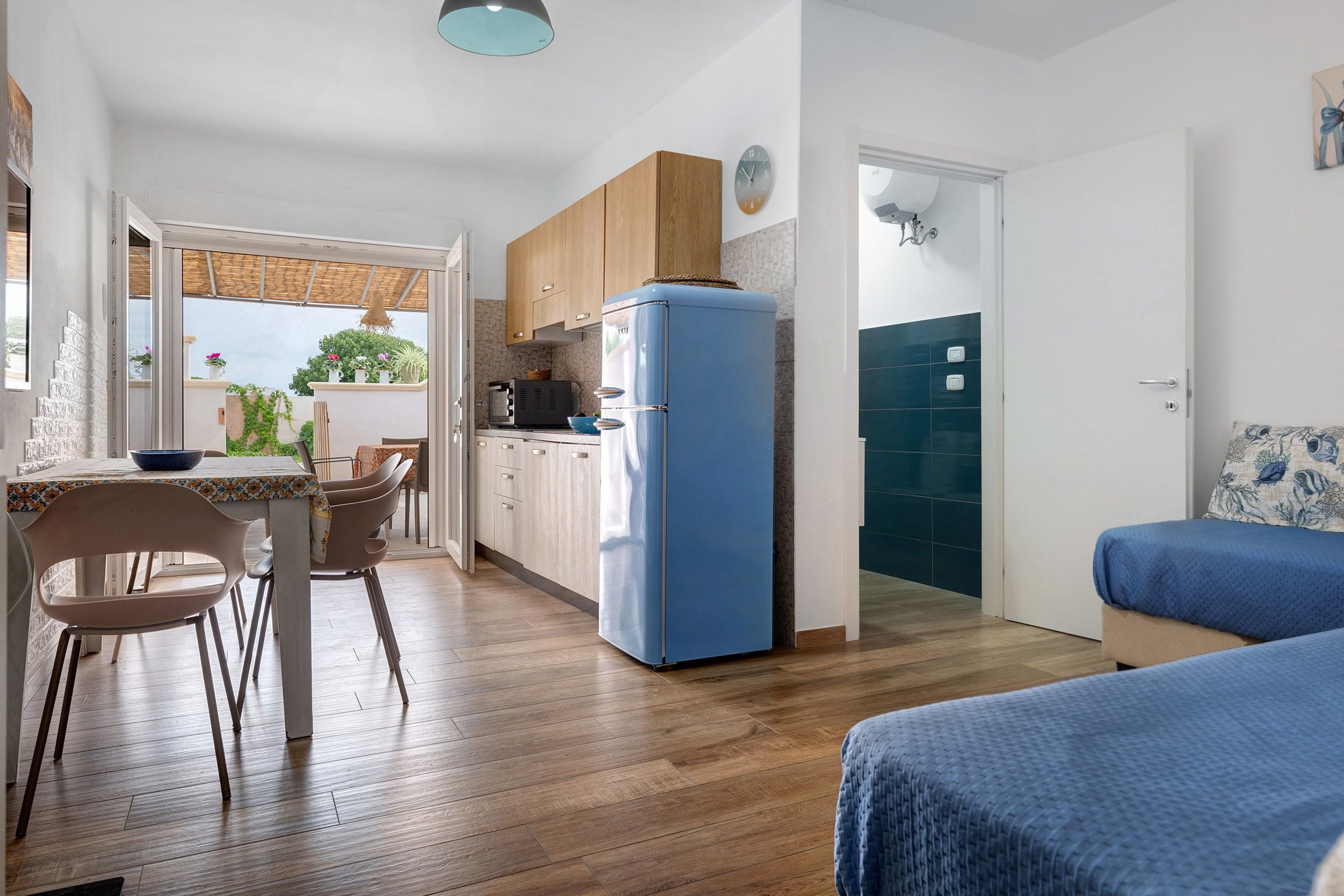 A compact living space with a kitchenette, a dining area, and a bedroom.