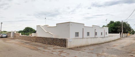 A single-story building with a flat roof, a stone wall, and a paved driveway.
