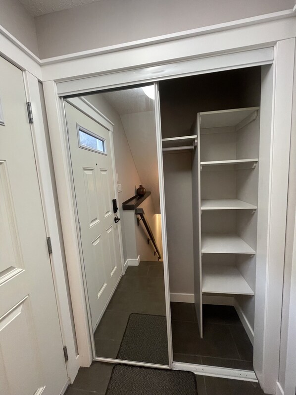 A walk-in closet with a sliding door, a small window, and a step leading to a staircase. - Hanuel’s Place is an elegant and cozy suite in Regina Saskatchewan, Canada (Regina)