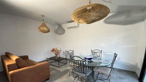 A modern living room with a brown sofa, a glass dining table with metal chairs, and two woven pendant lights. - Very comfortable, bright T3 in a quiet location with a beautiful exterior. (Occhiatana)