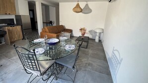 A modern kitchen with a built-in oven, a dining area with a glass table and metal chairs, and a living room with a sofa and a decorative vase. - Very comfortable, bright T3 in a quiet location with a beautiful exterior. (Occhiatana)